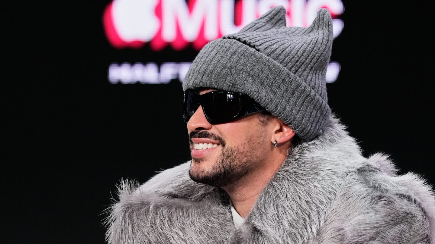 Bad Bunny wears black sunglasses and a grey beanie at an Apple Music event