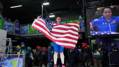 Elana Meyers Taylor holds up an American flag in celebration.