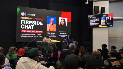 Two people speaking on stage in front of an audience.
