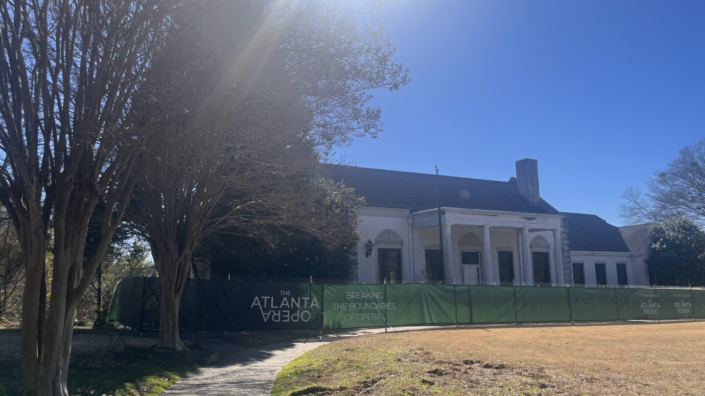 Bobby Jones Clubhouse behind fencing with Atlanta Opera signage on the Atlanta Beltline under bright sun.
