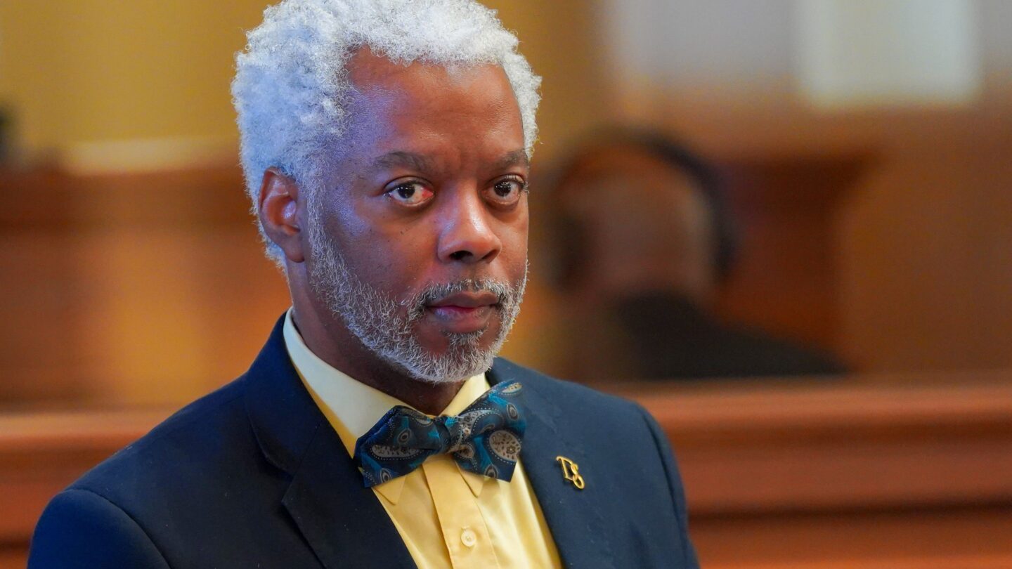 state representative dexter sharper stands in a suit with a yellow shirt and bow tie