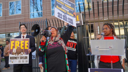 Community members hold up signs advocating for Rodney Taylor's release in front of federal building.