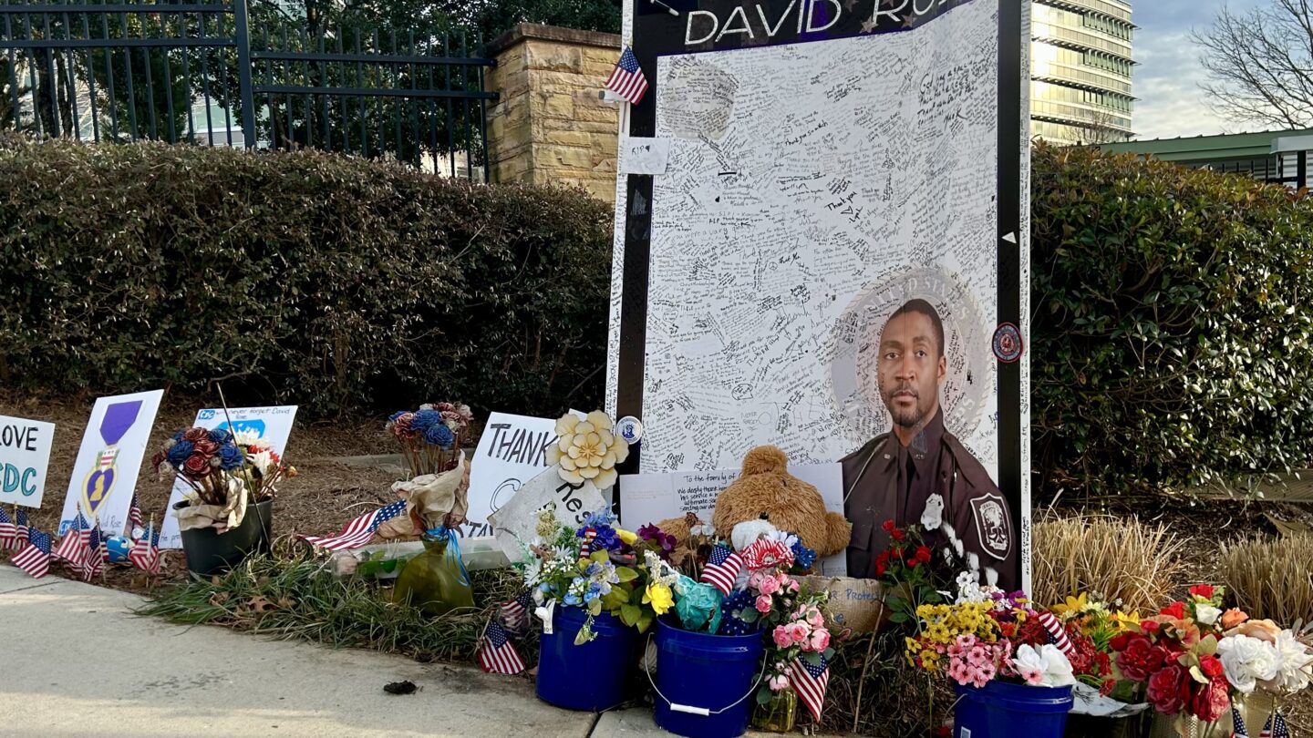 A memorial outside CDC headquarters pays tribute to DeKalb County Police Officer David Rose, killed last summer by a man who had expressed 'discontent' with COVID-19 vaccines. Investigators say the shooter killed Rose before killing himself (WABE/Jess Mador)