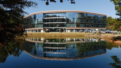 A hemisphere building with floor to ceiling glass windows next to a body of water
