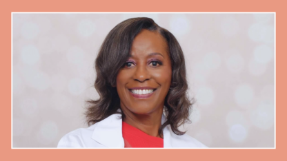 A portrait of a doctor wearing an orange shirt and a white coat