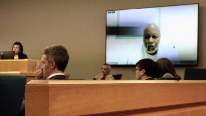An evidentiary hearing with a large TV screen for Danyel Smith to appear