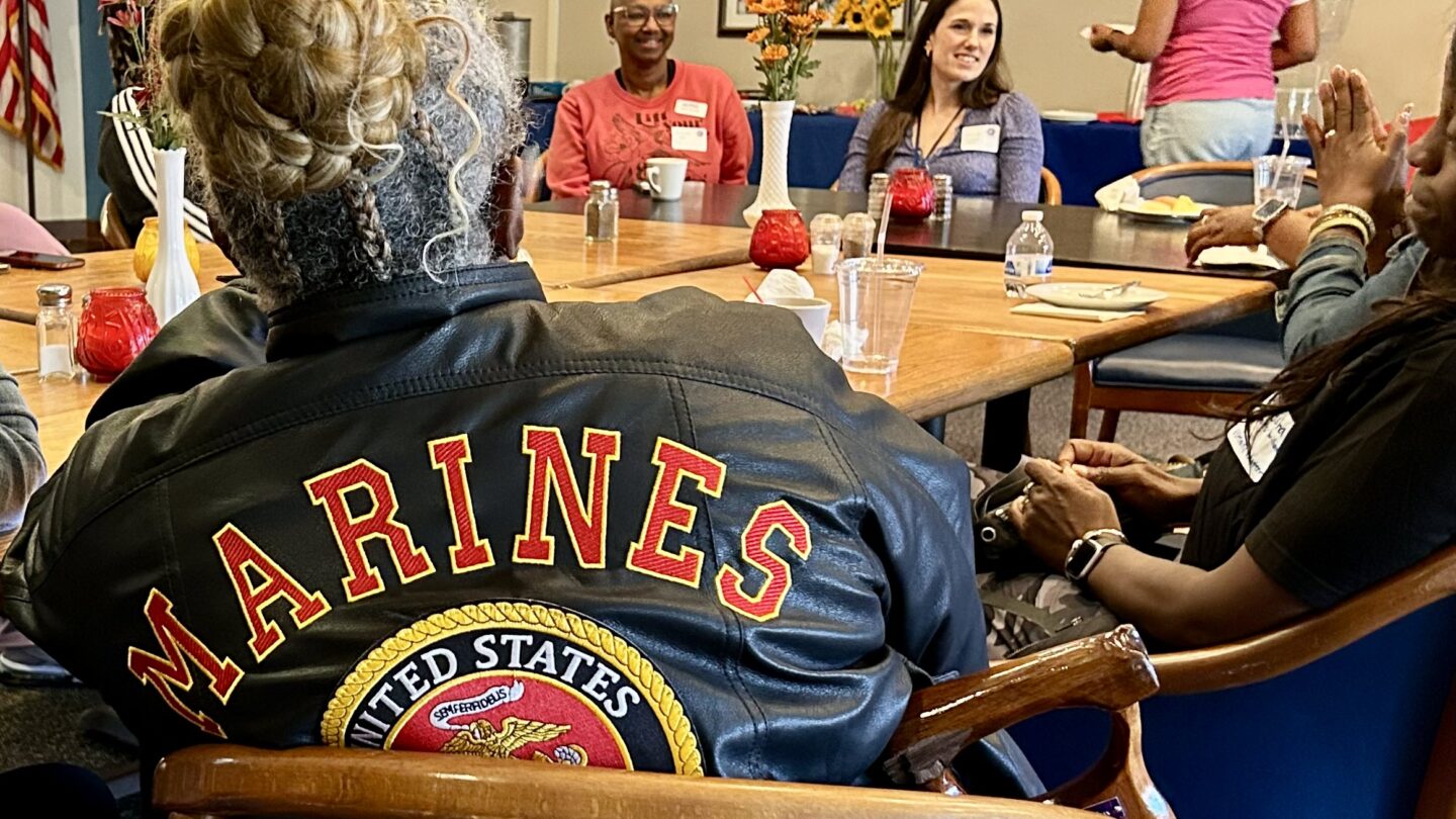 women service members sit around a wooden table.