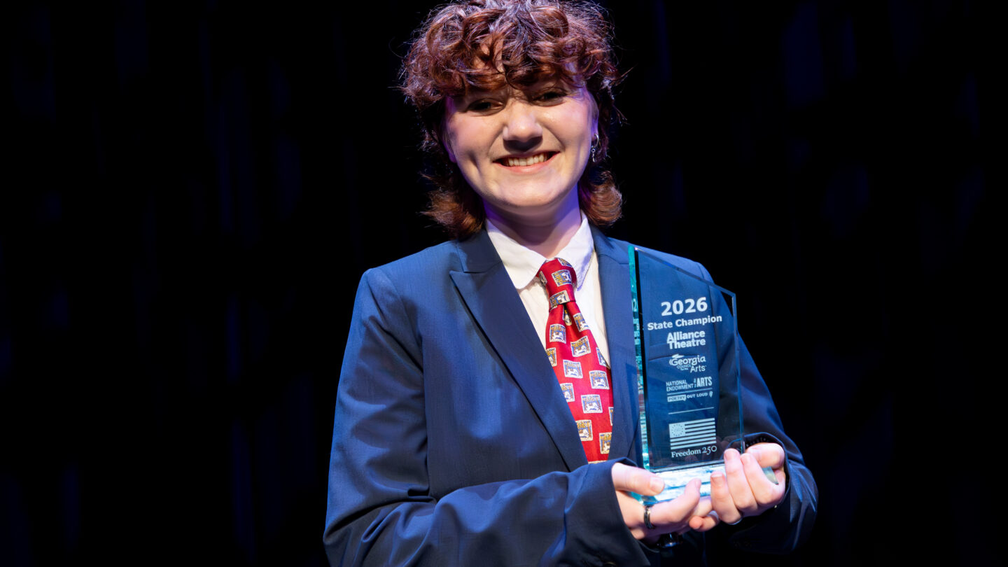 Rory Berg holds her 2026 state champion trophy on stage at the Woodruff Arts Center