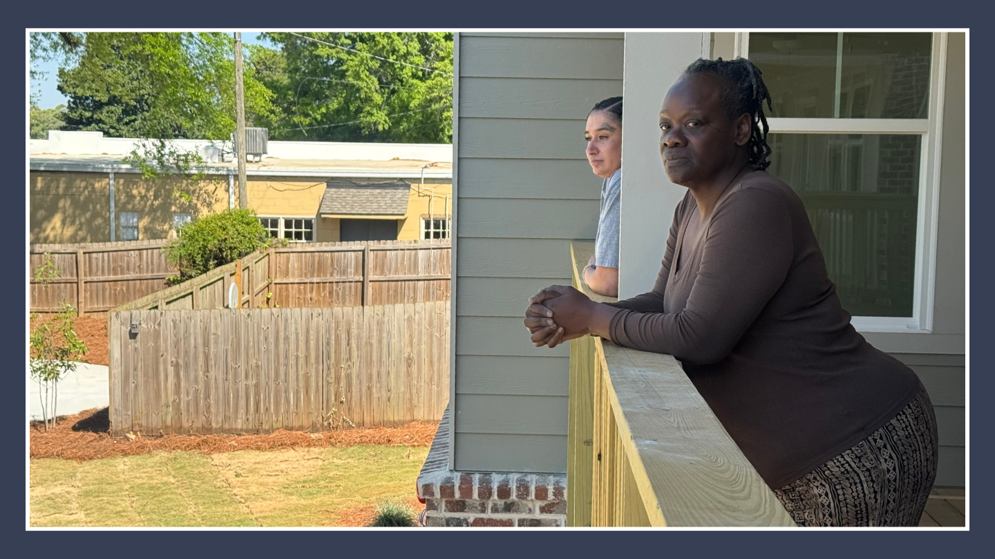 Two people lean out of their balconies to look at the backyard