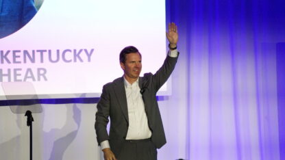 Andy Beshear waves on stage.