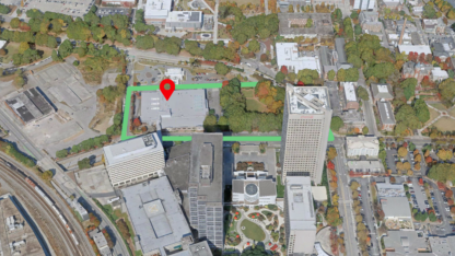 A map with a green square and a red place marker on top of a building in a neighborhood of buildings