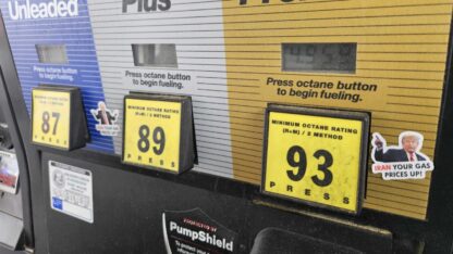 A gas pump is shown with stickers on it showing president donald trump