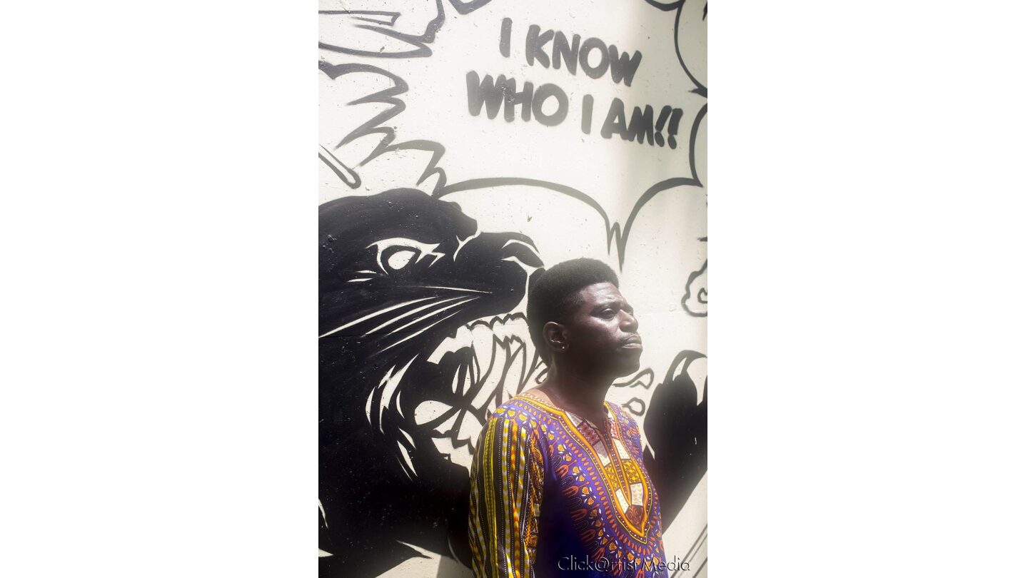 Singer-songwriter Donnie stands before a mural of a roaring panther beside the words ‘I Know Who I Am.’