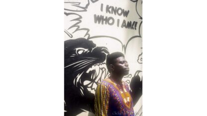 Singer-songwriter Donnie stands before a mural of a roaring panther beside the words ‘I Know Who I Am.’