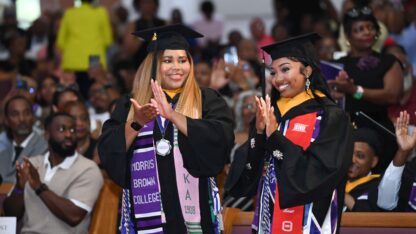 Morris Brown College valedictorian Faith Shamley (left) stands with salutatorian Tyrianna Johnson cap in a black graduation cap and gown.