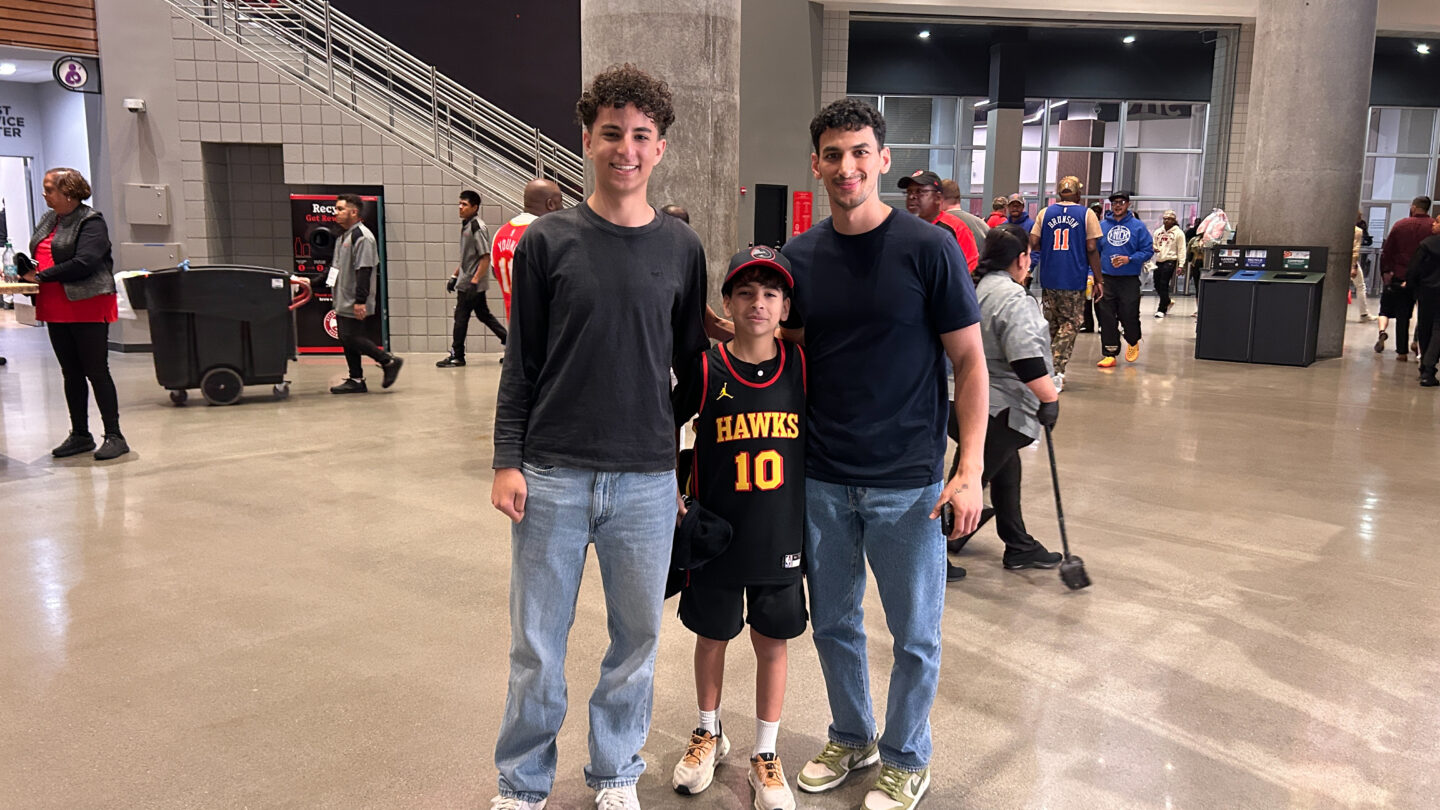 A family of three stand in a large lobby