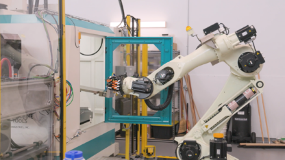 A white robot arm works on a machine