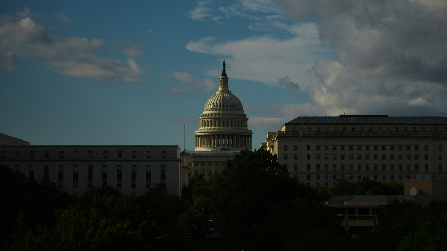 A building is seen in the distance surrounded by blue sky and white clouds
