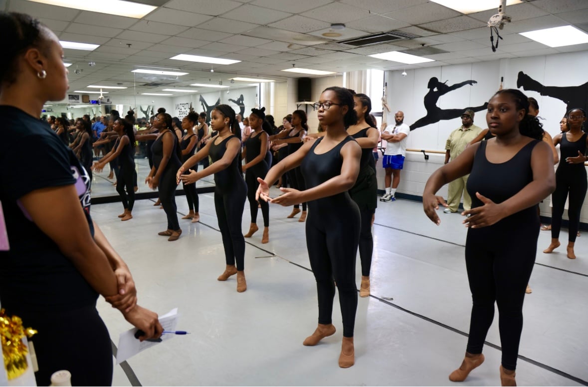 A group of dancers in a room with mirrors.
