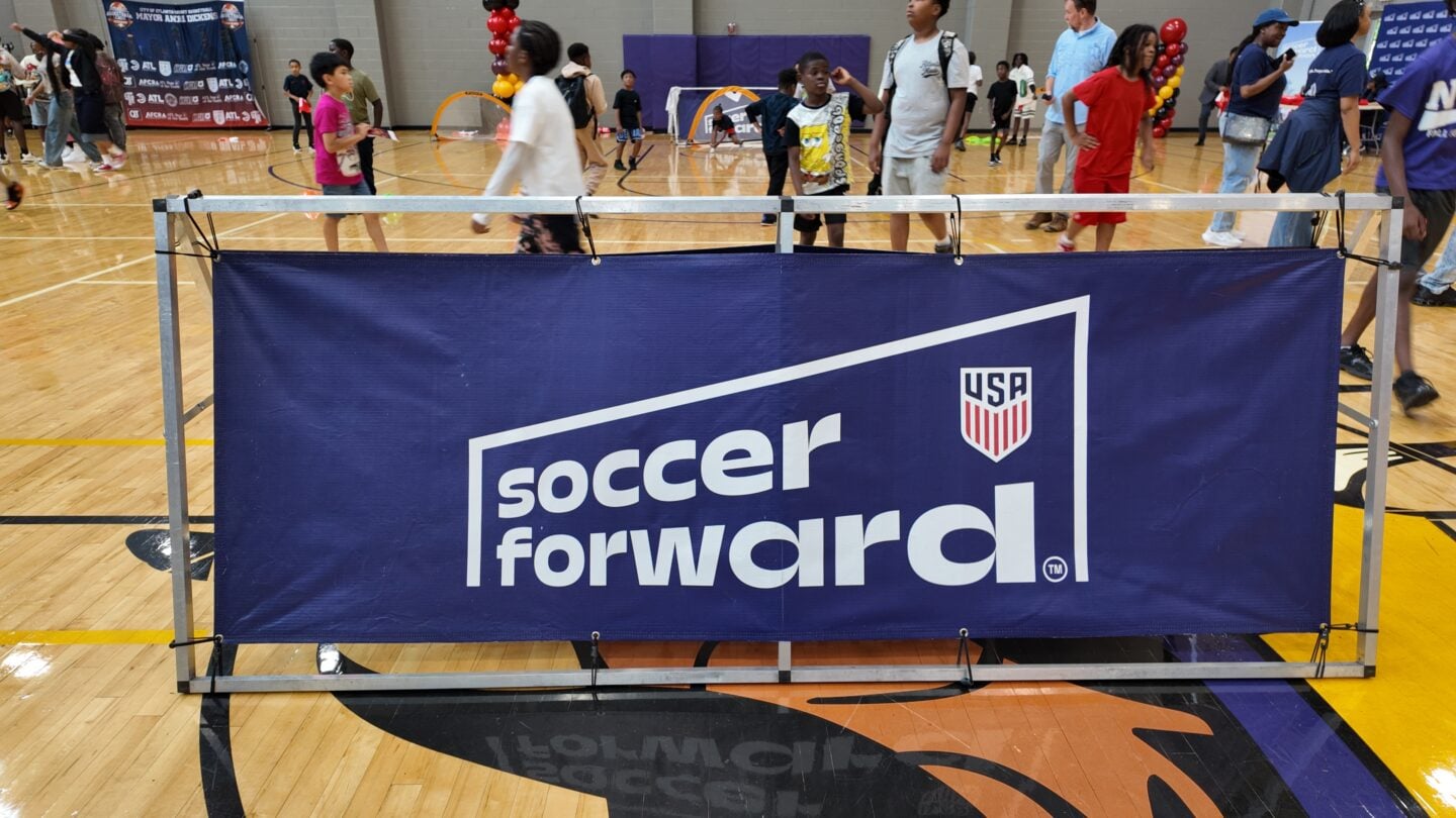 A soccer forward sign as kids play in the background.