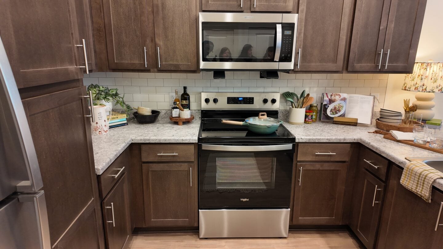 A greyish dark wood paneled kitchen in an apartment.