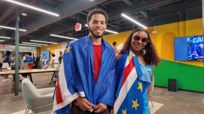 Two people wearing the blue, red, and white flag of Cabo Verde.