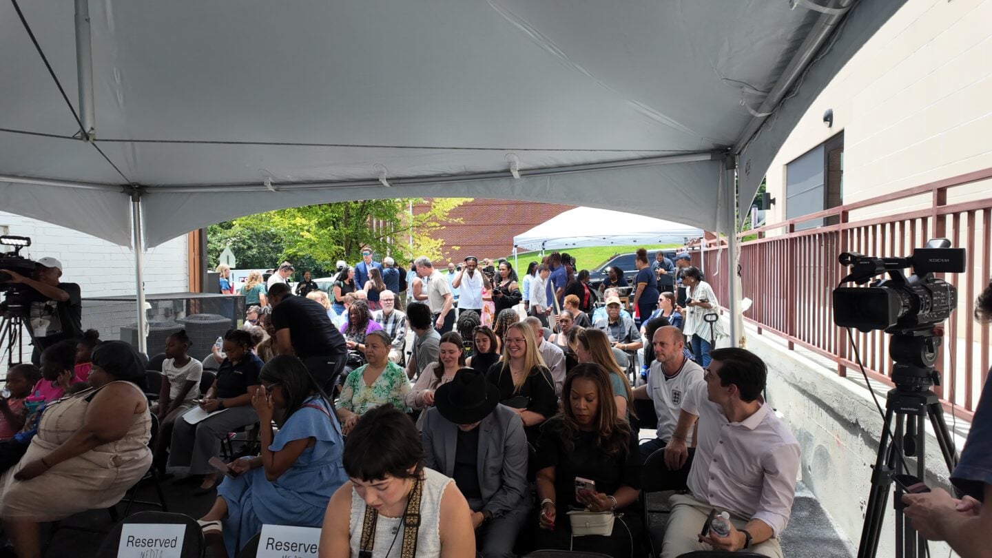 A group of community members and residents sitting under a tent to celebrate the opening of a new residential area.