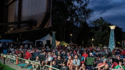 A large gathering of people crowd around a screen to watch the World Cup outside