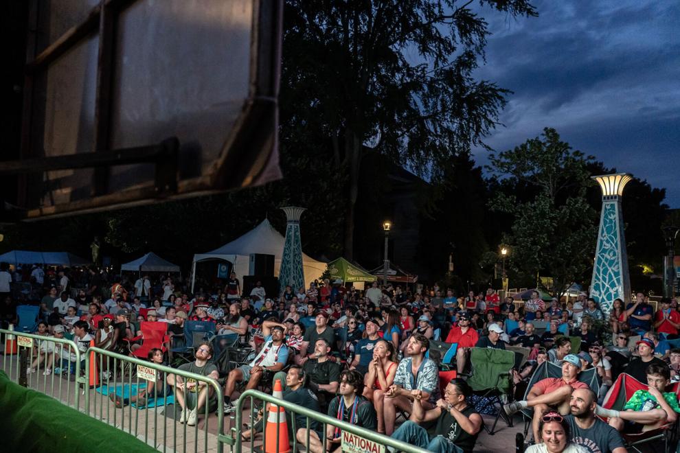 A large gathering of people crowd around a screen to watch the World Cup outside