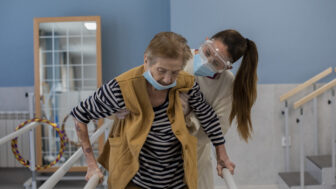 An elderly patient is assisted by a health care worker