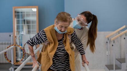 An elderly patient is assisted by a health care worker