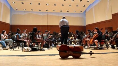 A conductor leads young string musicians rehearsing on the Atlanta Symphony Hall stage